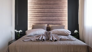 Ein ordentlich bezogenes Bett mit einer beigefarbenen Tagesdecke, zwei Kissen und einer gefalteten Decke.