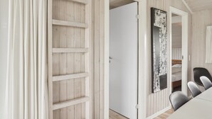 Habitació amb un mur amb panells de fusta, una porta blanca, un llit amb capçalera i una cadira negra.