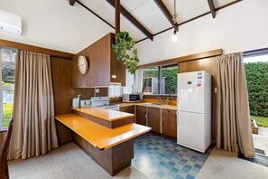 Une cuisine compacte avec un comptoir en bois, un four à micro-ondes, un réfrigérateur et une horloge murale.