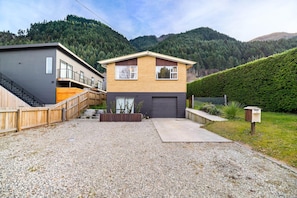 A two-story house with a gravel driveway, a wooden fence, and a mailbox. - Character Retro Family home in Queenstown (Queenstown)