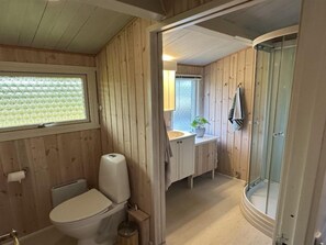 Bathroom features a toilet, shower with glass door, and a window with a unique bubble pattern.