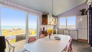 A modern kitchen with a large island, sliding glass doors to a balcony, and a view of the ocean.