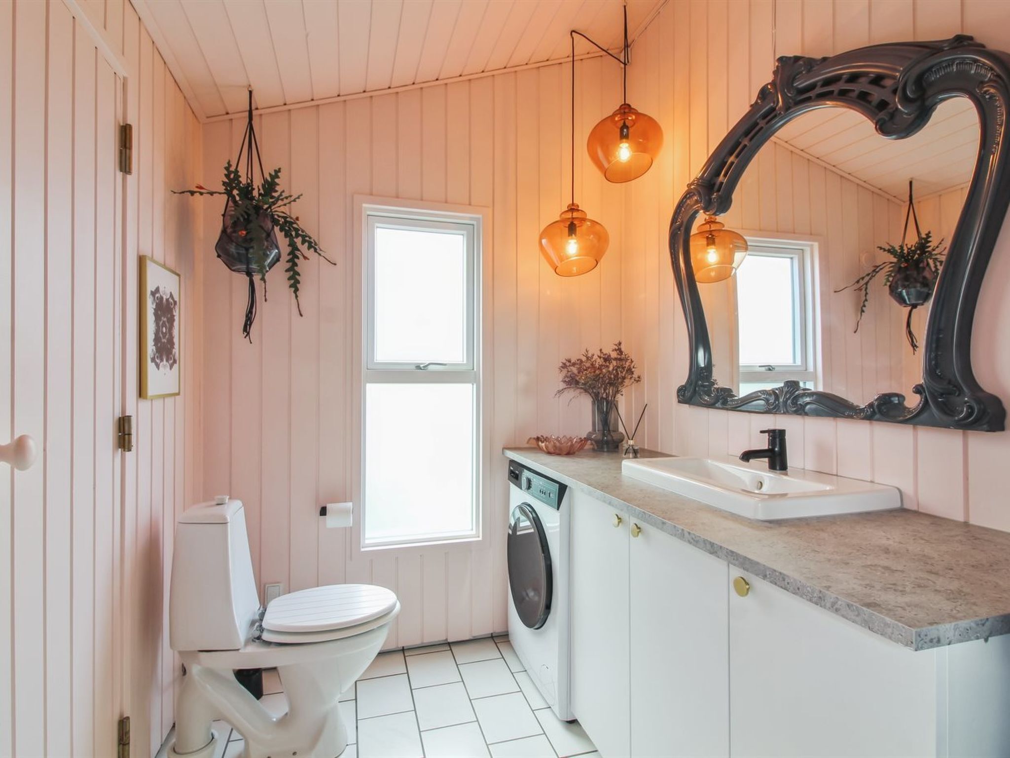 A bathroom with a white toilet, a washing machine, a sink, and a large mirror.