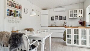 A modern kitchen with white cabinetry, a dining area with a white table and chairs, and a hanging light fixture. - "Thorlak" - 860m from the sea by Interhome (Væggerløse)
