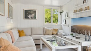 A modern living room with a white sofa, a glass coffee table, and a large flat-screen TV. - "Thorlak" - 860m from the sea by Interhome (Væggerløse)