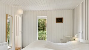 A bedroom with a large bed, a door leading to a balcony, a small table with a lamp, and a framed picture on the wall. - "Thorlak" - 860m from the sea by Interhome (Væggerløse)