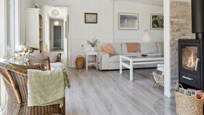 A cozy living room with a fireplace, a sofa, a coffee table, and a wicker chair. - "Thorlak" - 860m from the sea by Interhome (Væggerløse)