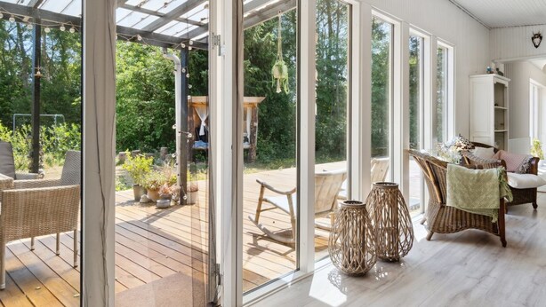 A spacious room with large sliding glass doors leading to an outdoor deck, wicker furniture, and a white interior. - "Thorlak" - 860m from the sea by Interhome (V æggerløse)