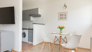 Ett modernt kök med grå skåp, en inbyggd tvättmaskin och en matplats med ett bord för två personer.