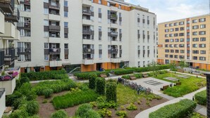 Un edifici residencial de diversos pisos amb balcons, un pati verd i una zona d'aparcament.