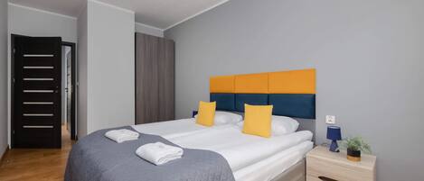 Un dormitorio moderno con una cama grande, una mesita de noche con lámpara y suelo de madera.