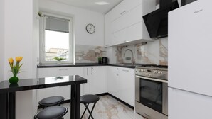 Una cocina moderna con gabinetes blancos, encimera negra, estufa y lavamanos.