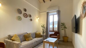 Una sala de estar con un sofá, una mesa de centro, un televisor y platos decorativos en la pared.