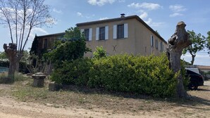 Una casa de dos pisos con fachada color crema, contraventanas blancas y techo de tejas.