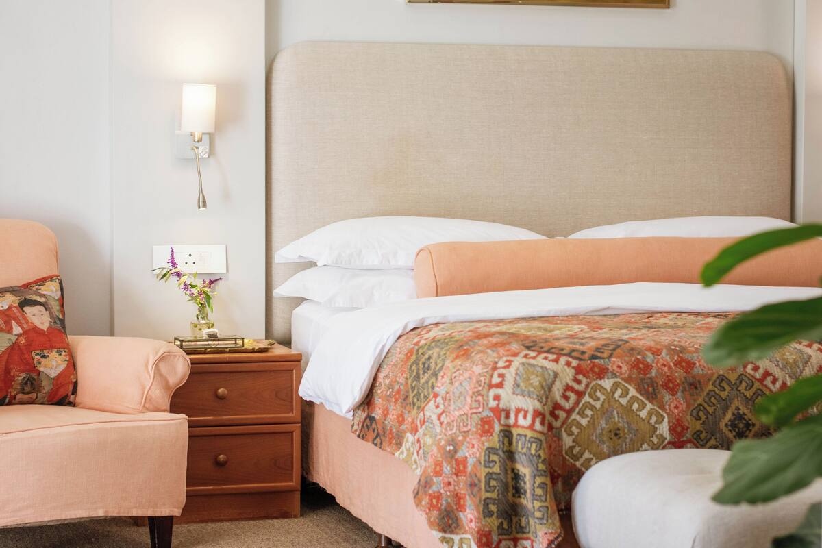 A neatly arranged bedroom with a bed, bedside table, and a chair.