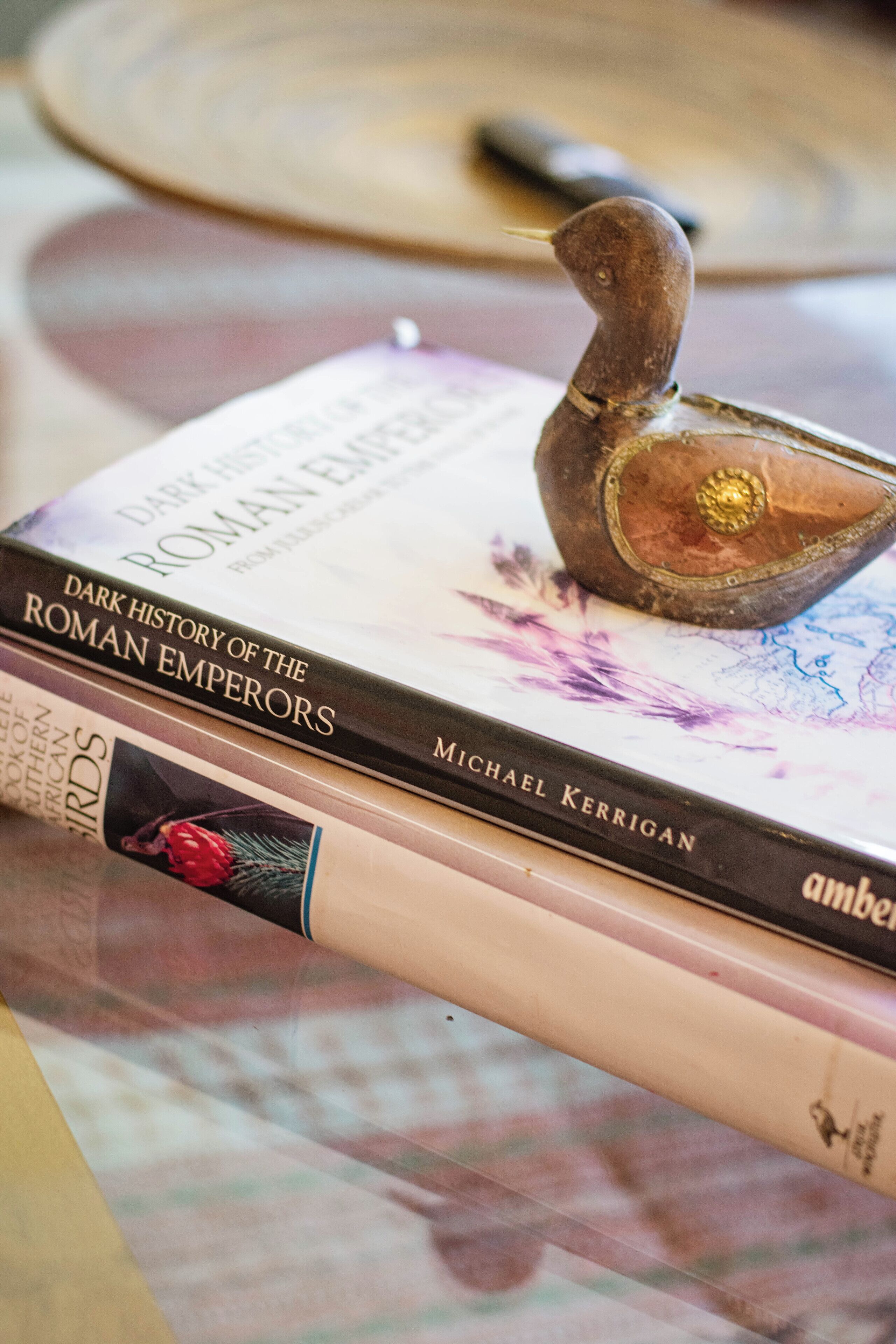 Un libro titulado 'Dark History of the Roman Emperors' de Michael Kerrigan, sobre una mesa con una cuchara de madera encima.