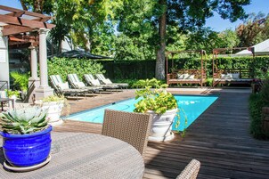 Una piscina al aire libre, sombrillas, sillones reclinables de piscina