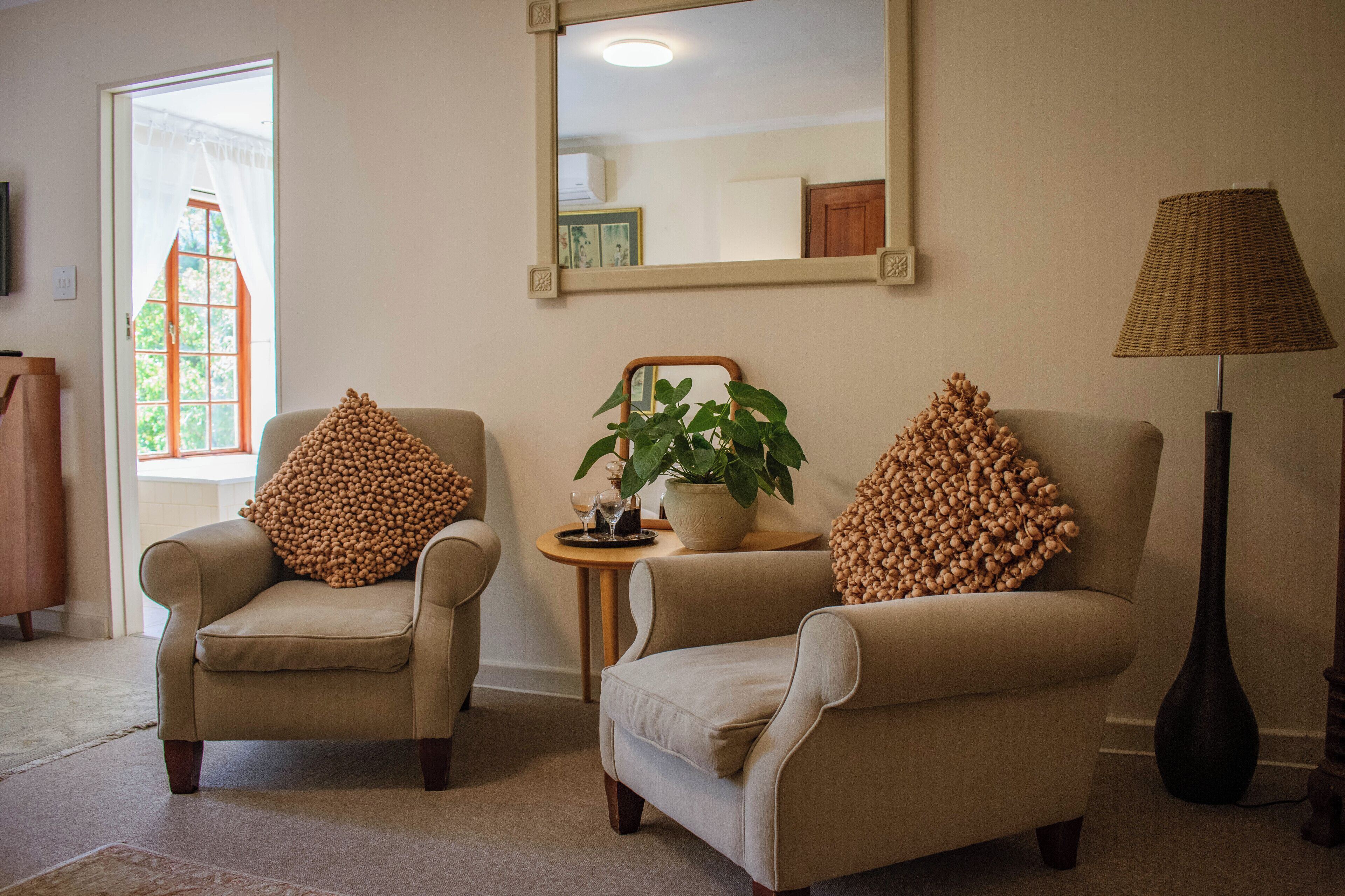 A living room with two armchairs, a side table with a plant, and a floor lamp.