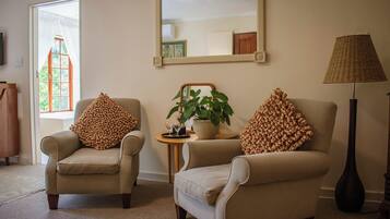 A living room with two armchairs, a side table with a plant, and a floor lamp.