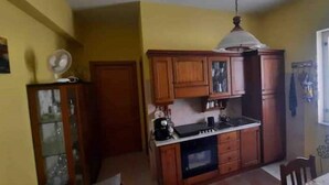 A compact kitchen with wooden cabinets, a built-in oven, and a window providing natural light. - Beachfront apartment on the western riviera (Milazzo)