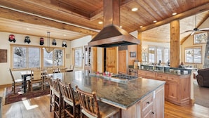 A spacious kitchen with a large island, wooden ceiling, and a view of snowy trees through the windows. - Silverado Lodge at Palisades - 4BR w/ Private Hot Tub, Ski Shuttle & Pet-Friendly! (Olympic Valley)