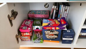 A shelf with various board games and trivia books. - Carlenes Getaway | Lake Views, Beach & Games Hub (Loch Sport)