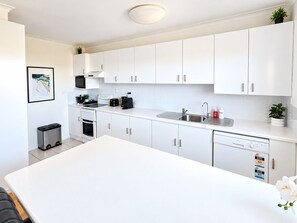 A modern kitchen with white cabinetry, a stainless steel sink, and a dishwasher.