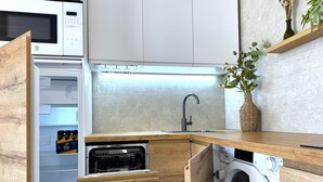 Une cuisine compacte équipée d’un four à micro-ondes encastré, d’un évier et d’un lave-linge.