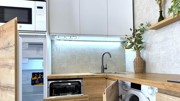 Una cocina compacta con microondas integrado, un lavabo y una lavadora.