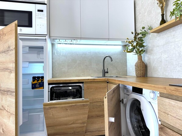A compact kitchen with a built-in microwave, a sink, and a washing machine. - Las Dunas DM ocean view (Maspalomas)