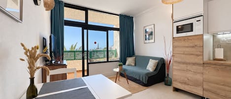 Una sala de estar moderna con sofá, mesa de comedor y zona de cocina.