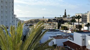 Zona residencial costera con edificios, una playa y palmeras.