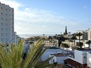 Une zone résidentielle côtière avec des immeubles, une plage et des palmiers.