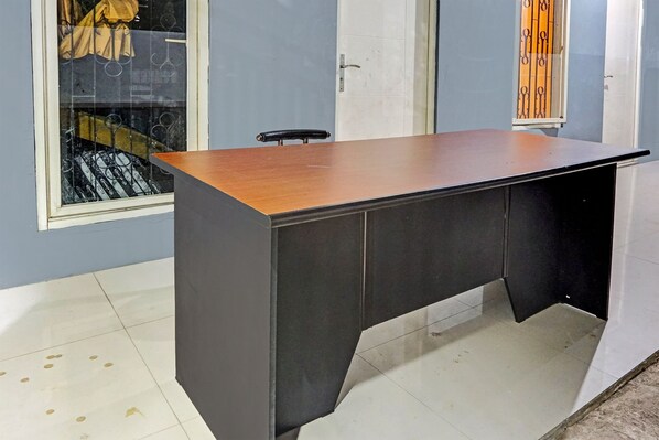 A room with a large wooden desk, a chair, a window with metal bars, and a door. - SPOT ON 91756 Alif House Syariah (Pandaan)
