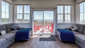 Una habitación iluminada por el sol con dos sofás, un ventanal corredero que da a un patio exterior y ventanas amplias.