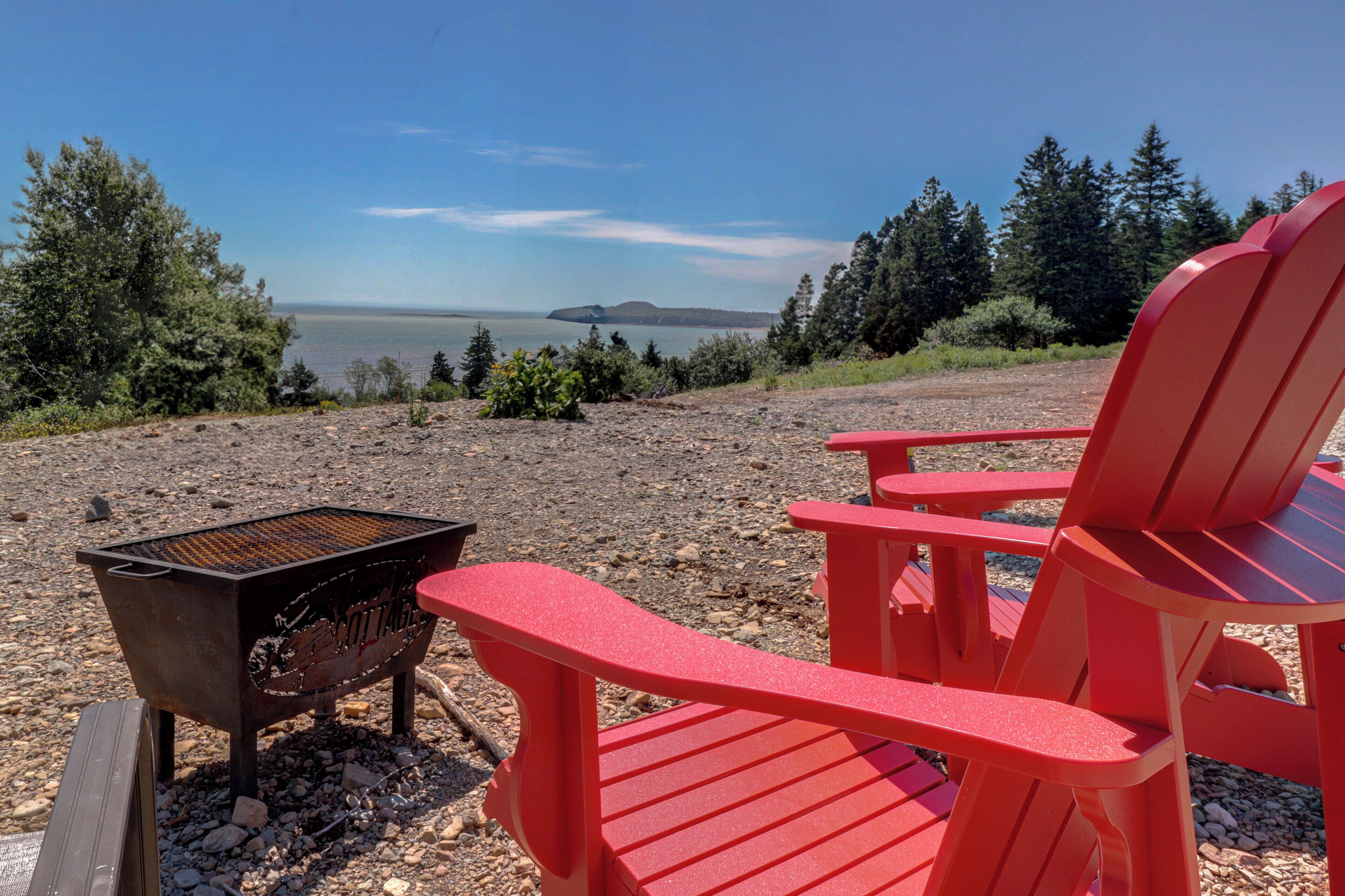 A scenic outdoor seating area with a grill and chairs overlooking a body of water.