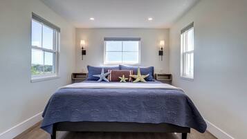 A bedroom with a large bed, two bedside tables, a window, and wall-mounted lights.
