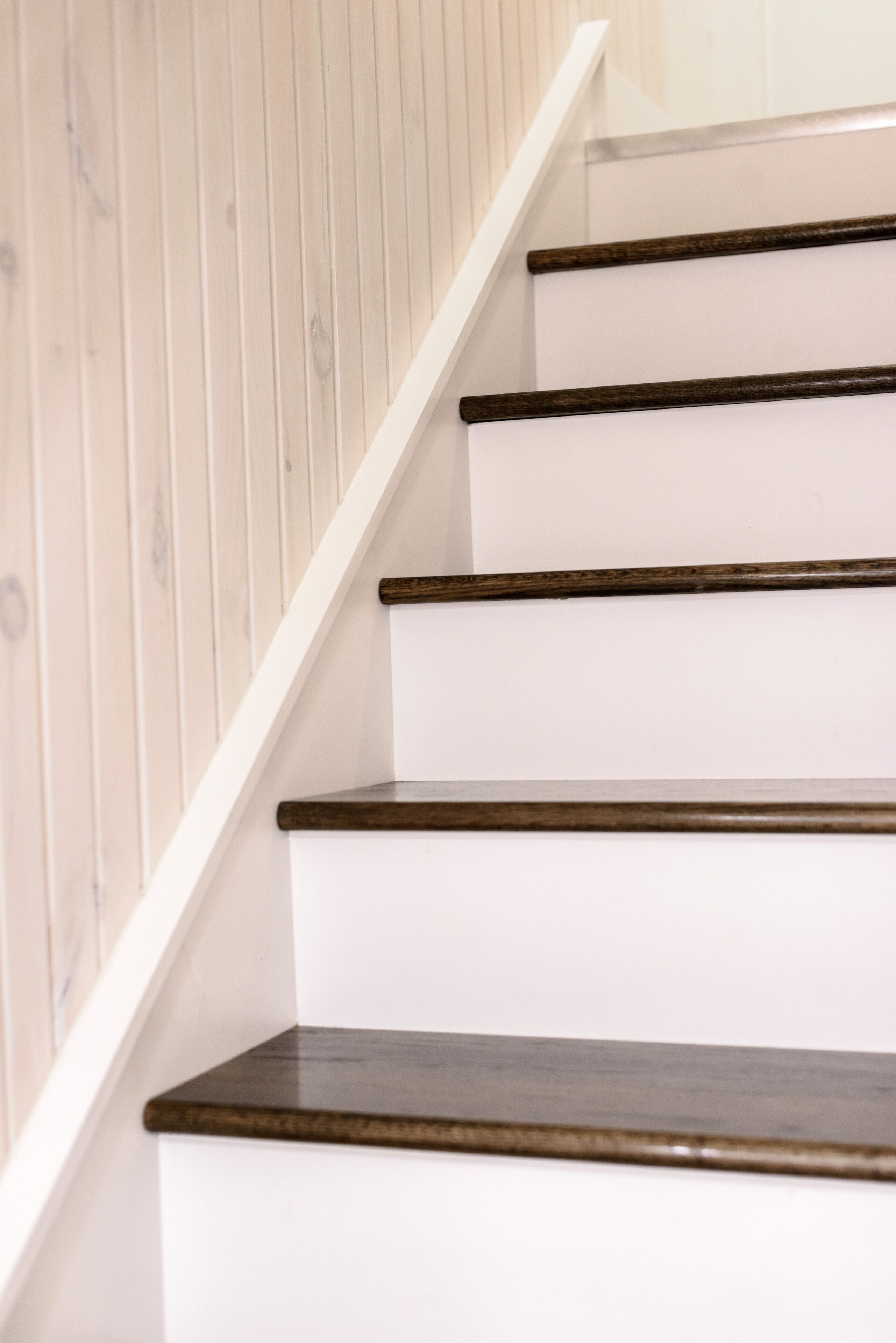 Una escalera con peldaños blancos y bordes de madera oscura.