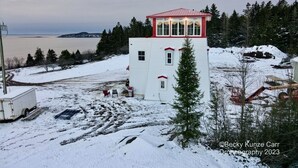 Un edificio blanco con techo rojo, probablemente un mirador o torre de observación, rodeado de terreno y árboles cubiertos de nieve.