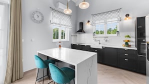 A modern kitchen with a marble island, black cabinets, and teal chairs. - Sienna Zminj in Krculi (Zminj)