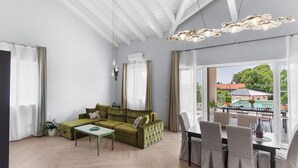 A modern living room with a green sofa, a dining table with chairs, and large windows offering a view of the outdoors. - Sienna Zminj in Krculi (Zminj)