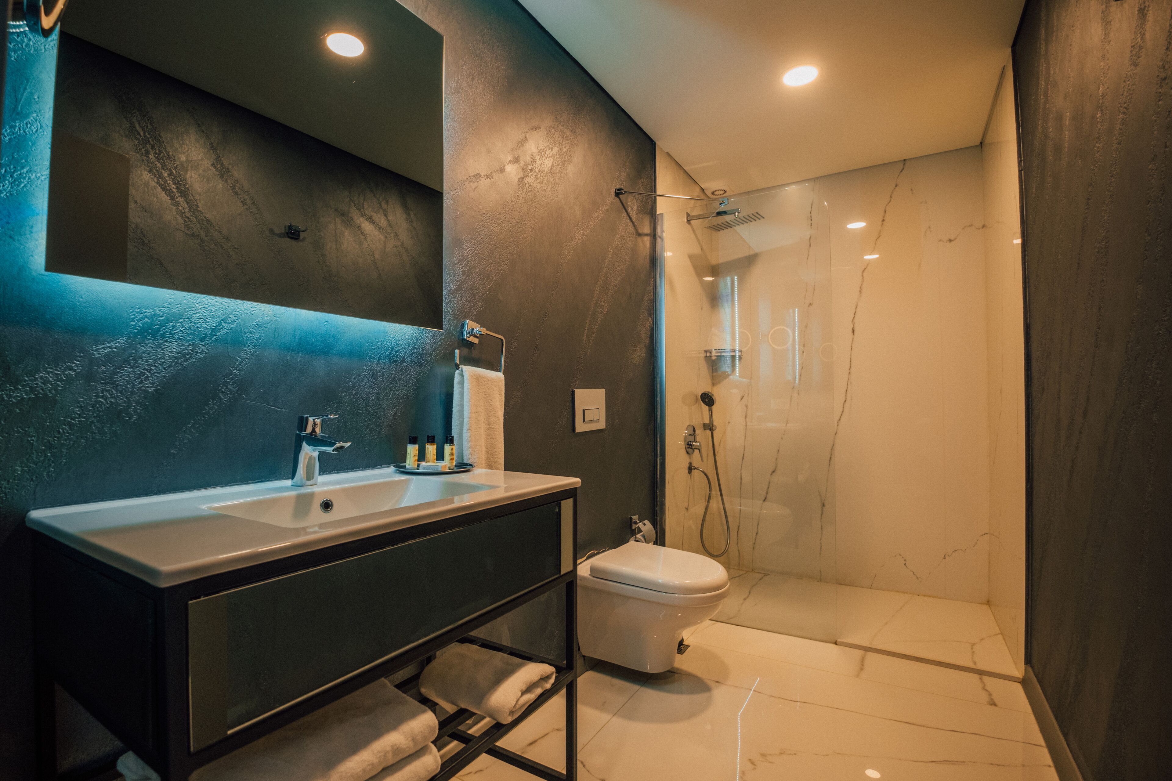 A modern bathroom with a large mirror, a sink, and a toilet.