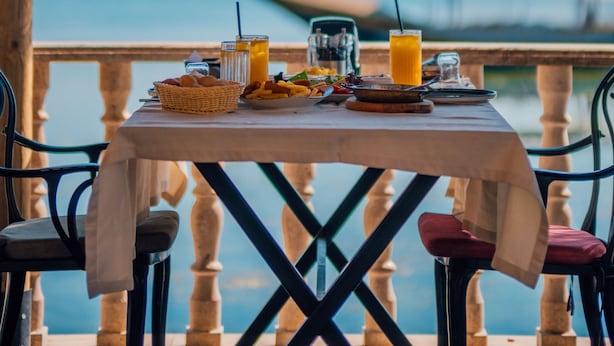 Une table dressée pour le petit-déjeuner, avec vue sur la mer et un bateau en arrière-plan.