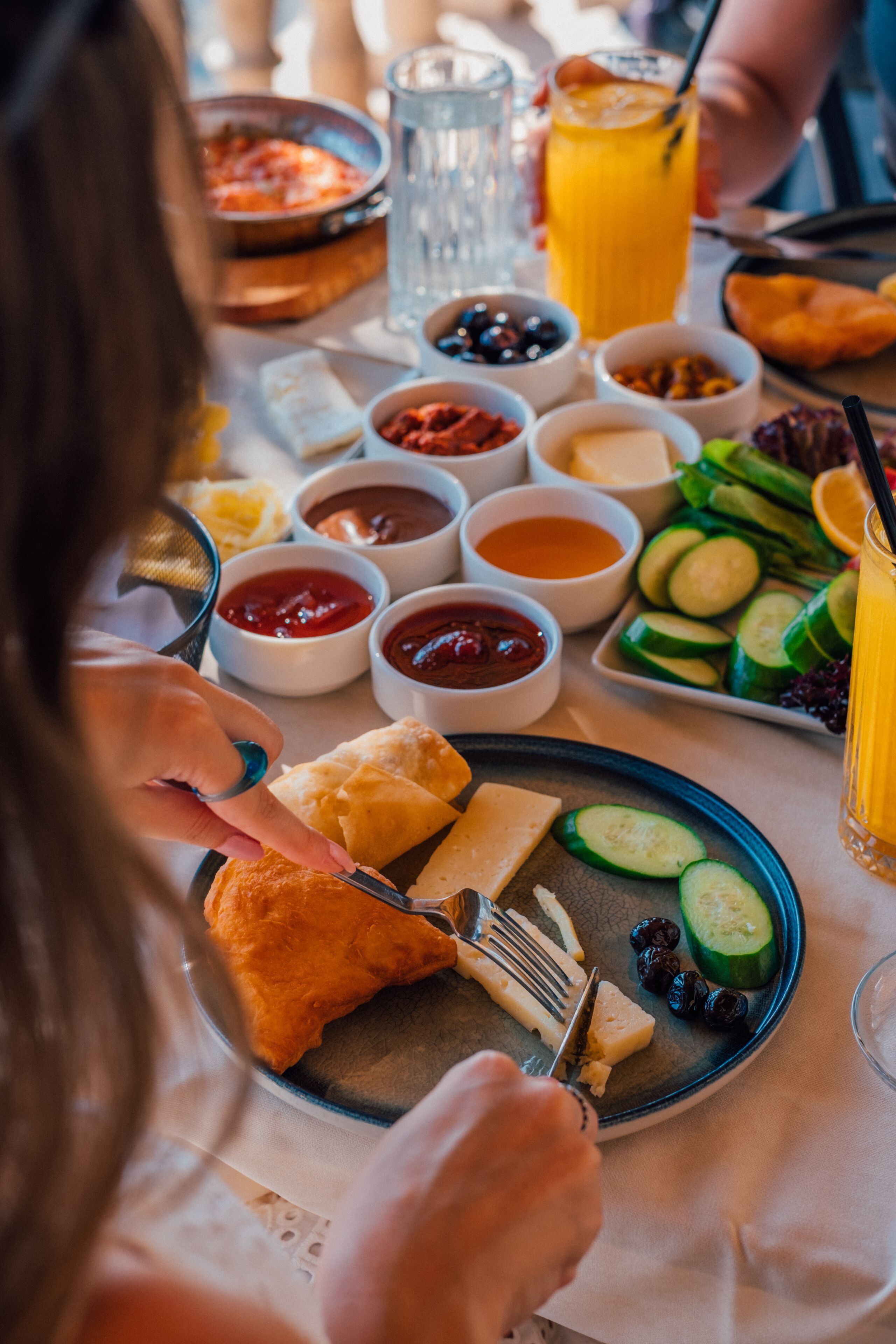 A table with various food items and condiments, including bread, cheese, and sliced cucumbers.