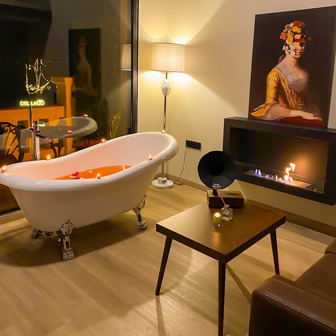 A modern bathroom with a freestanding bathtub, a wall-mounted TV, and a decorative lamp.