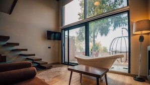 Un salon moderne avec une grande fenêtre, une baignoire et un escalier.