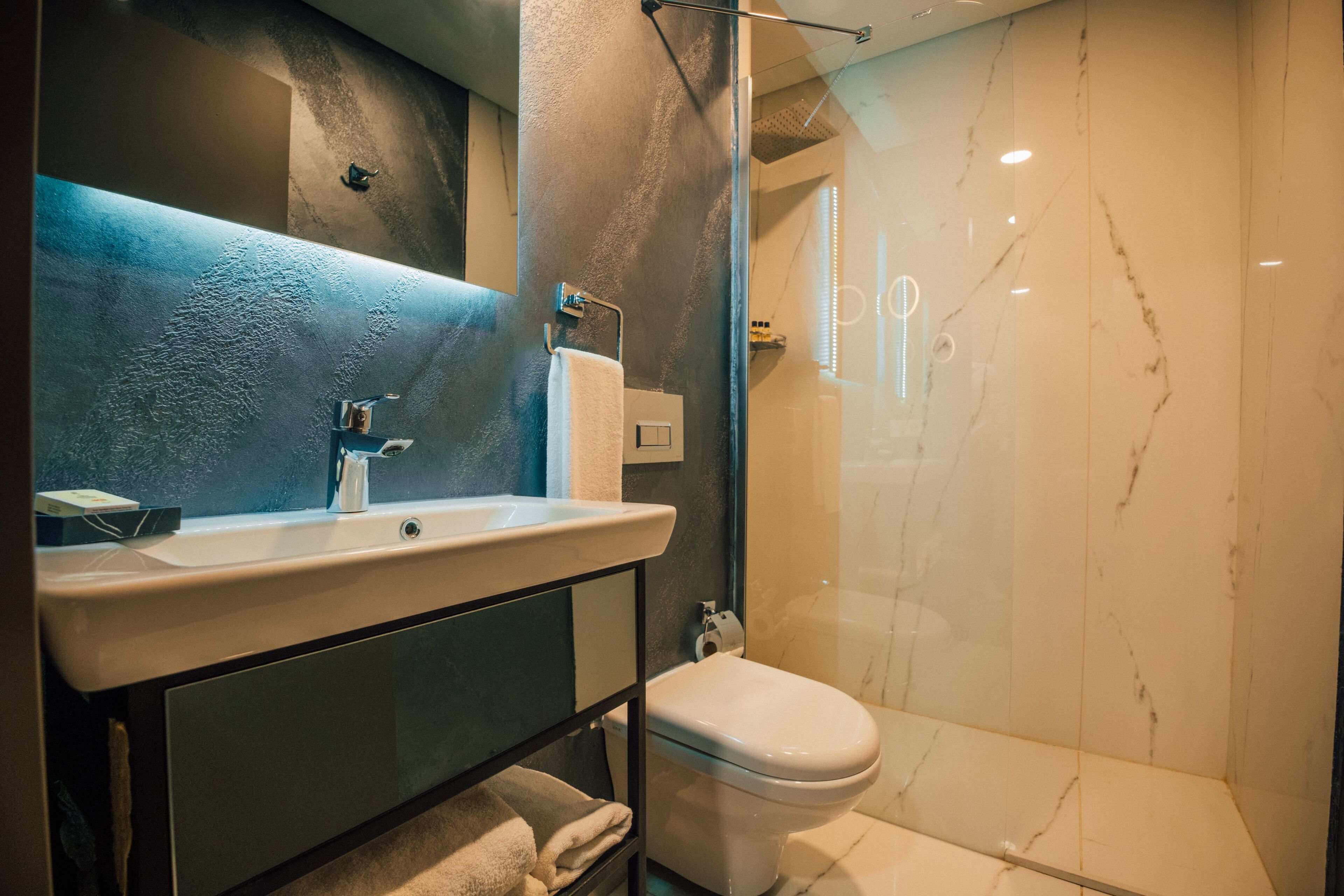 A modern bathroom with a glass shower enclosure, a white sink, and a toilet.