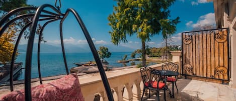 A patio with a swing set, a table with chairs, and a view of the sea.