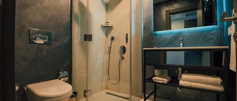 Un baño moderno con ducha de vidrio, inodoro y lavamanos con espejo.