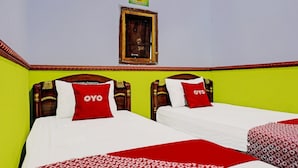 A hotel room with two beds, each with a wooden headboard and red pillows.